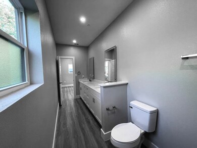 Full bath with a textured wall, dark wood-type flooring, and double vanity