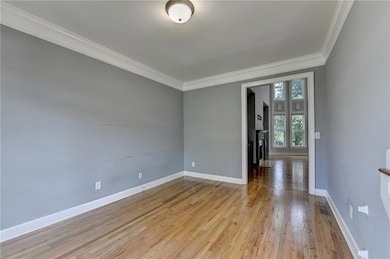 Empty room featuring ornamental molding and wood finished floors