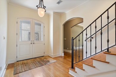 Entrance foyer with crown molding, french doors, and light hardwood / wood-style flooring