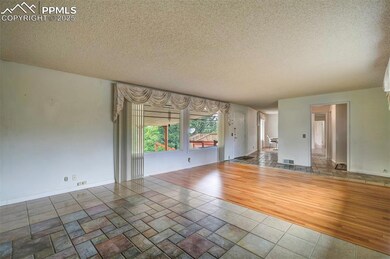 Unfurnished living room with a textured ceiling, baseboards, and wood finished floors
