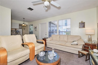 Living room featuring carpet and a ceiling fan