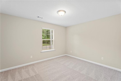 Empty room featuring carpet floors, baseboards, and a textured ceiling