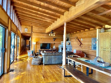Living room featuring wood walls, wood-type flooring, ceiling fan, and wood ceiling