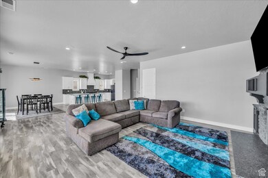 Living area featuring a ceiling fan, recessed lighting, light wood-type flooring, and a fireplace