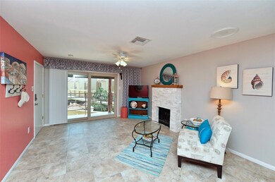 Living room with wood burning fireplace, all tile floors, sliding door to balcony with pool and gulf views