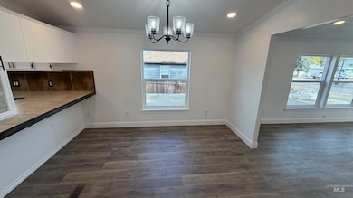 Unfurnished dining area with recessed lighting, ornamental molding, a chandelier, and dark wood-type flooring