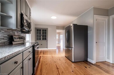 Renovated kitchen with new stainless steel appliances, granite counter tops, new cabinetry and refinished hardwood floors. Built-in china cabinet and doorway leading to living room to the left. To the right, doorway leading to basement.