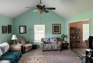 Living room featuring ceiling fan, vaulted ceiling