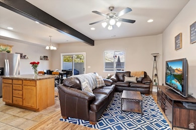 Living area with beamed ceiling, recessed lighting, light wood-style floors, a chandelier, and ceiling fan