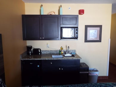 Kitchen with a sink, black microwave, and dark cou