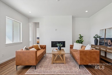 Living room with a glass covered fireplace, plenty of natural light, wood finished floors, and recessed lighting