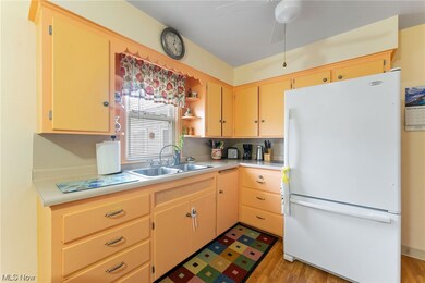Kitchen with light hardwood / wood-style flooring, light brown cabinetry, ceiling fan, sink, and white fridge