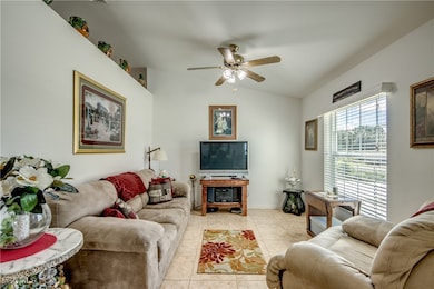 Living room with tile patterned flooring, ceiling fan, and lofted ceiling