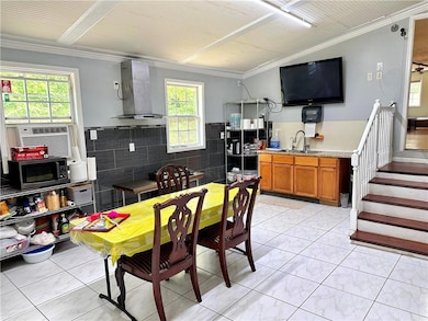 Kitchen and kitchen room with wall chimney exhaust hood, a sink, ornamental molding, brown cabinetry, and plenty of natural light