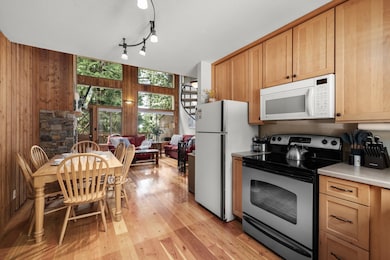 Kitchen featuring white appliances, light wood-style flooring, light countertops, track lighting, and wood walls