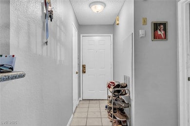 Doorway with light tile patterned floors and a tex