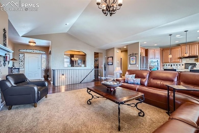 Living room featuring lofted ceiling, carpet flooring, and a chandelier