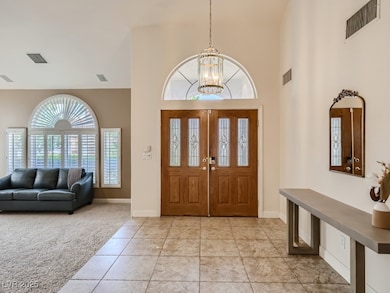 Entrance foyer featuring light tile patterned flooring, a high ceiling, light carpet, and a chandelier