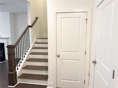 Stairway with wood finished floors and a glass covered fireplace