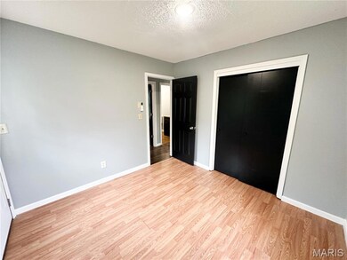 Unfurnished bedroom with a textured ceiling, a closet, and light wood-style floors