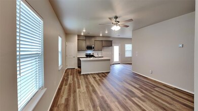 Kitchen with a ceiling fan, wood finished floors, a kitchen island with sink, gray cabinets, and stainless steel appliances