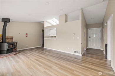 Open-flow floor plan connects the living area, kitchen, and entryway seamlessly. Vaulted ceilings and recessed lighting enhance the sense of space and natural light.