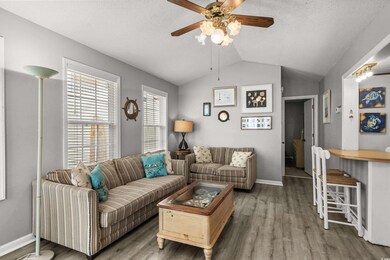Living area featuring wood finished floors, a ceiling fan, vaulted ceiling, baseboards, and a textured ceiling