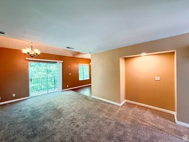 Spare room featuring a chandelier and carpet