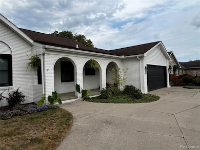 View of side of home with brick siding, driveway, roof with shingles, and a garage