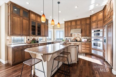 Kitchen with a kitchen island, a kitchen bar, hanging light fixtures, glass insert cabinets, and light stone counters