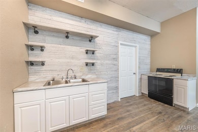 Kitchen with open shelves, electric range, wood finished floors, white cabinets, and light countertops