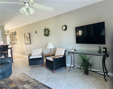 Living area with ceiling fan and baseboards