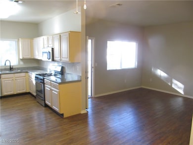 Kitchen with appliances with stainless steel finishes, dark wood-type flooring, open floor plan, and dark stone counters