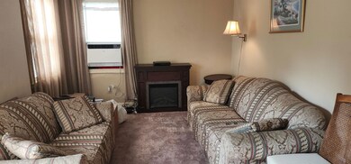 Carpeted living room featuring a fireplace and cooling unit