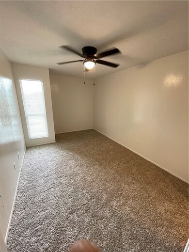 Carpeted empty room with a ceiling fan and a textu