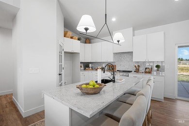 Kitchen with wood finished floors, tasteful backsplash, light stone counters, and high vaulted ceiling