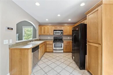 Kitchen featuring stainless steel appliances, light countertops, light tile patterned flooring, recessed lighting, and arched walkways