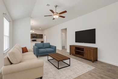 Living room featuring light wood finished floors, ceiling fan, and a chandelier