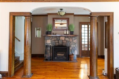 Hardwood floored living room featuring a textured ceiling, a wood burning fireplace, ornamental molding, and radiator heating unit