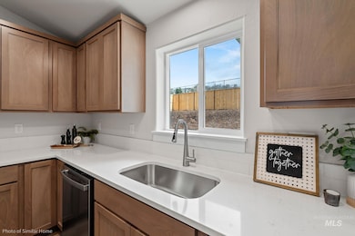 Kitchen featuring stainless steel dishwasher, light countertops, vaulted ceiling, and brown cabinets
