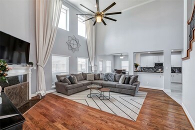 Staged-Custom drapes adorn the two stories of windows from floor to ceiling in this open-concept living room.