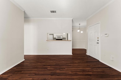 Unfurnished living room featuring dark wood-style flooring, ornamental molding, and a textured ceiling