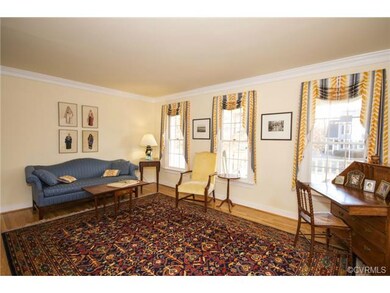 The formal living room faces the front of the house, with hardwood floors, crown molding, and lots of windows.