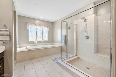 Primary bathroom with light tile floors, a shower with an upgraded showerhead and a seating bench, vanity, and an oversized bath