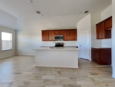 Kitchen featuring tasteful backsplash, a kitchen island with sink, appliances with stainless steel finishes, brown cabinets, and recessed lighting