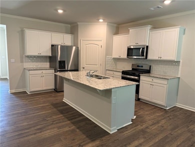 Kitchen with stainless steel appliances, white cabinets, ornamental molding, backsplash, and recessed lighting