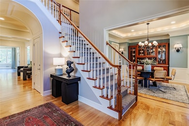 Wonderful first impression! View of the stately foyer with grand staircase and beautiful paneled archway adds to the dramatic and charming appeal!