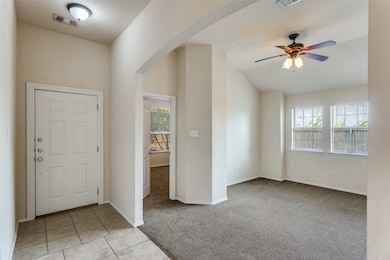 Foyer entrance featuring light colored carpet, light tile patterned flooring, healthy amount of natural light, a ceiling fan, and lofted ceiling
