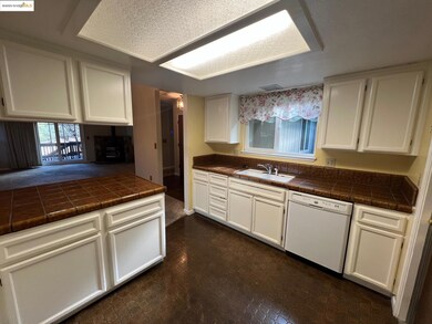 Kitchen with white cabinets, dishwasher, and tile counters