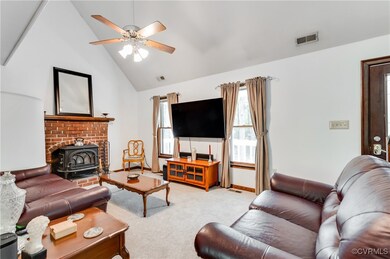 Living room featuring a wood stove, a ceiling fan,